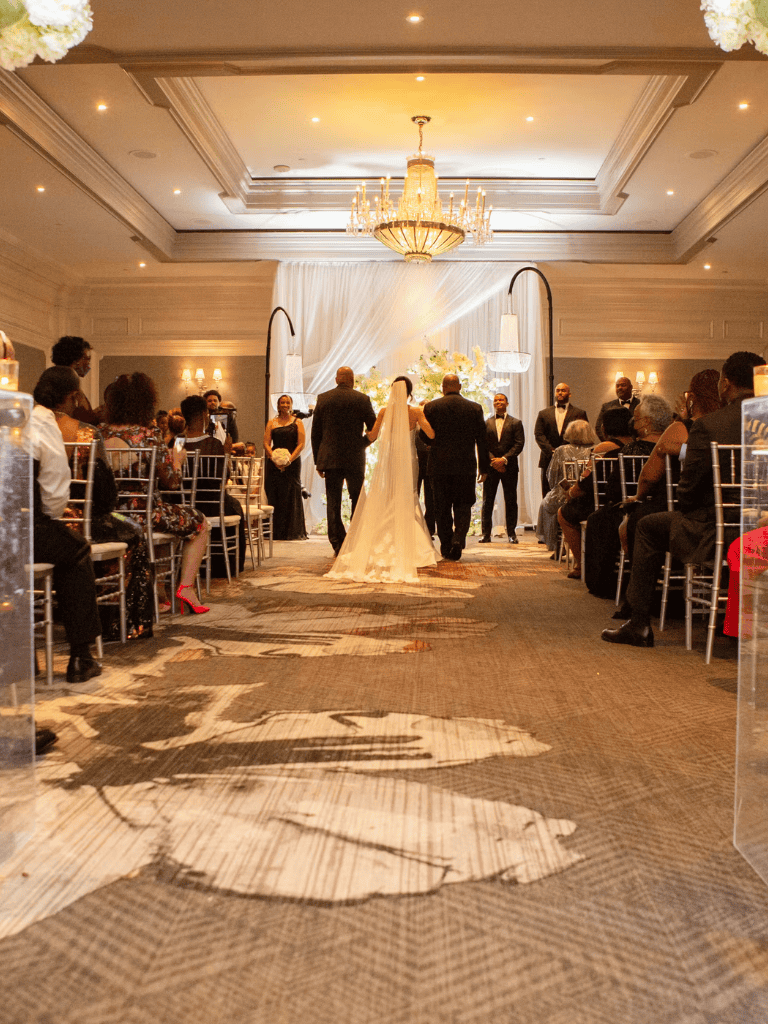 Elegant wedding ceremony in a luxurious banquet hall with chandeliers and floral decor.