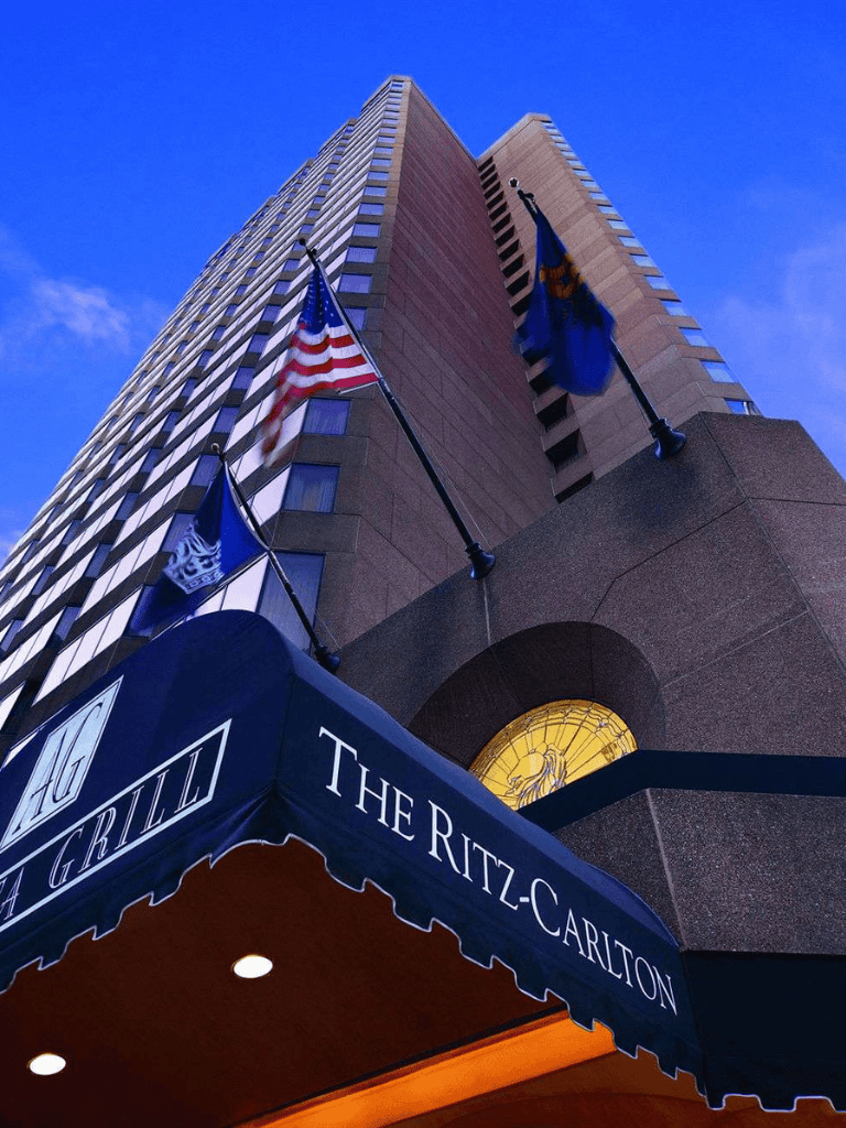 Modern skyscraper with flags and Ritz-Carlton entrance, downtown skyline, cityscape, travel, luxury hotel.