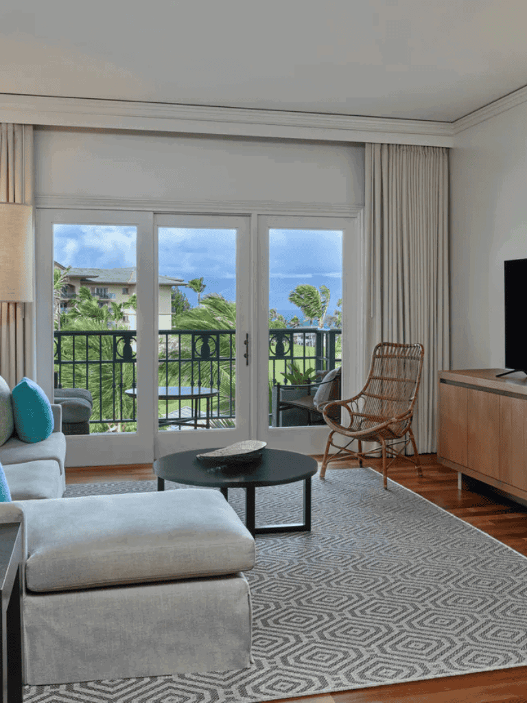Modern tropical living room with balcony view, stylish furniture, and lush greenery outside.
