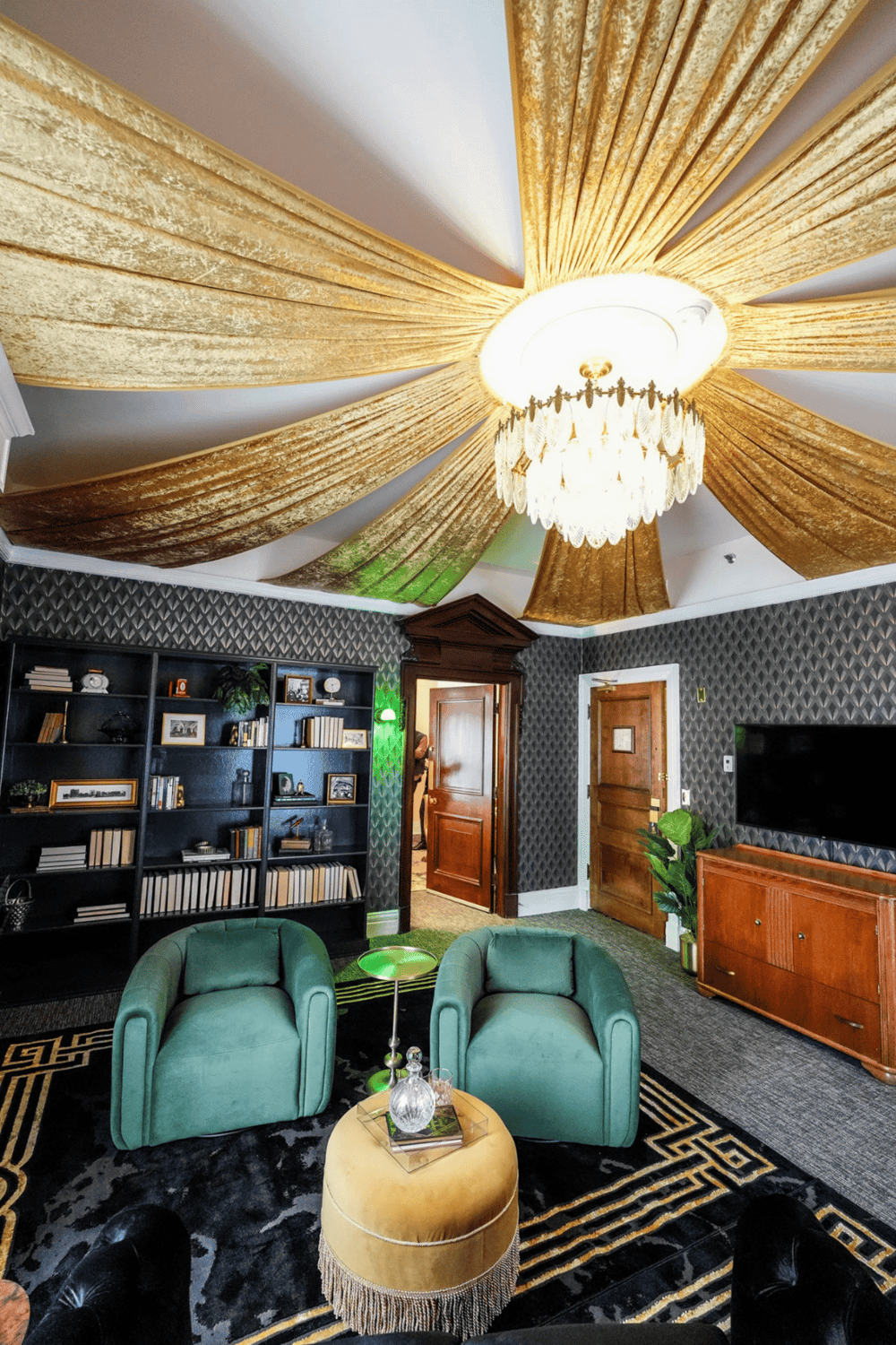 Elegant chandelier with gold drapery ceiling decor in sophisticated hotel lounge.