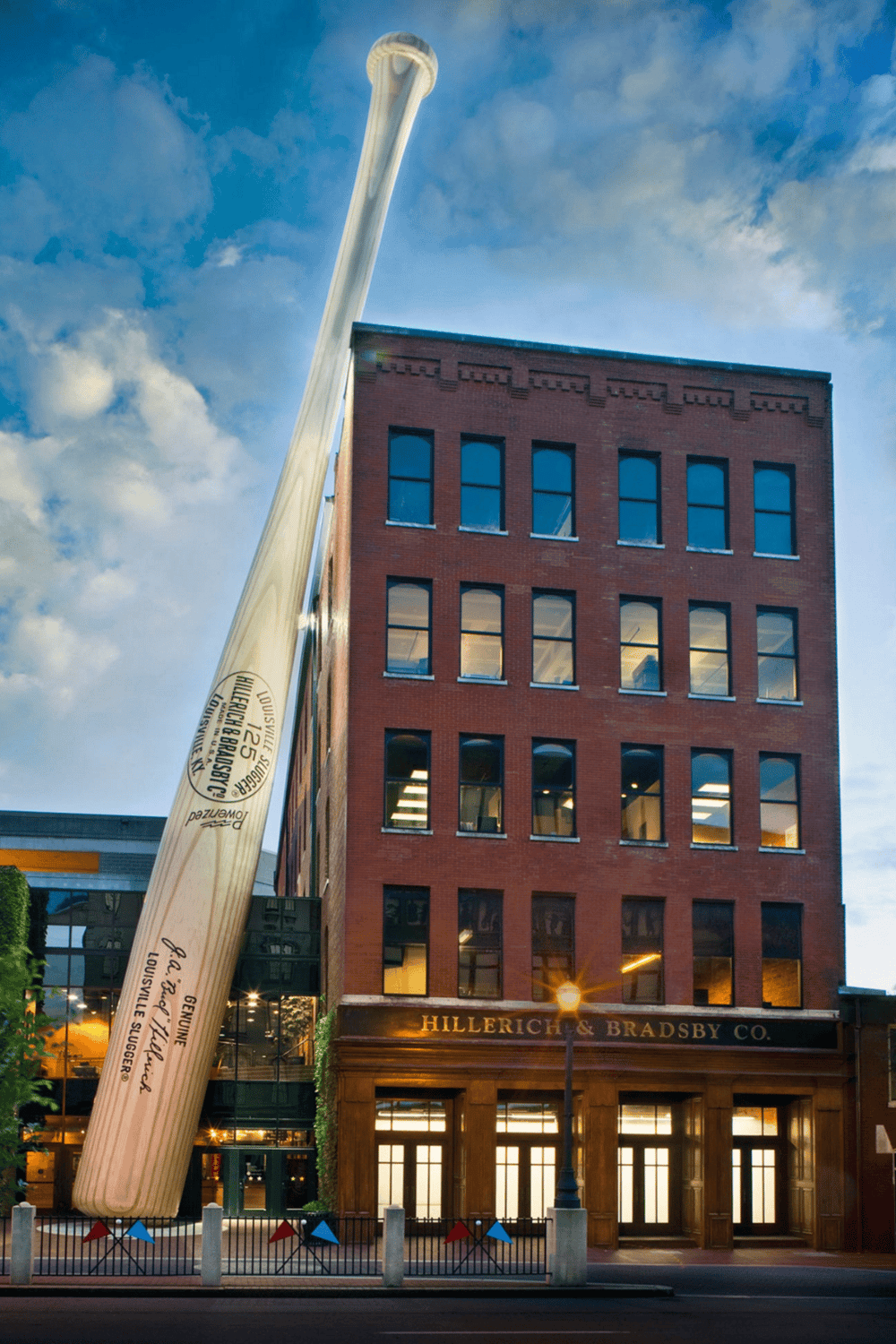 Large outdoor Louisville Slugger baseball bat sculpture in front of historic brick building, iconic Louisville landmark.