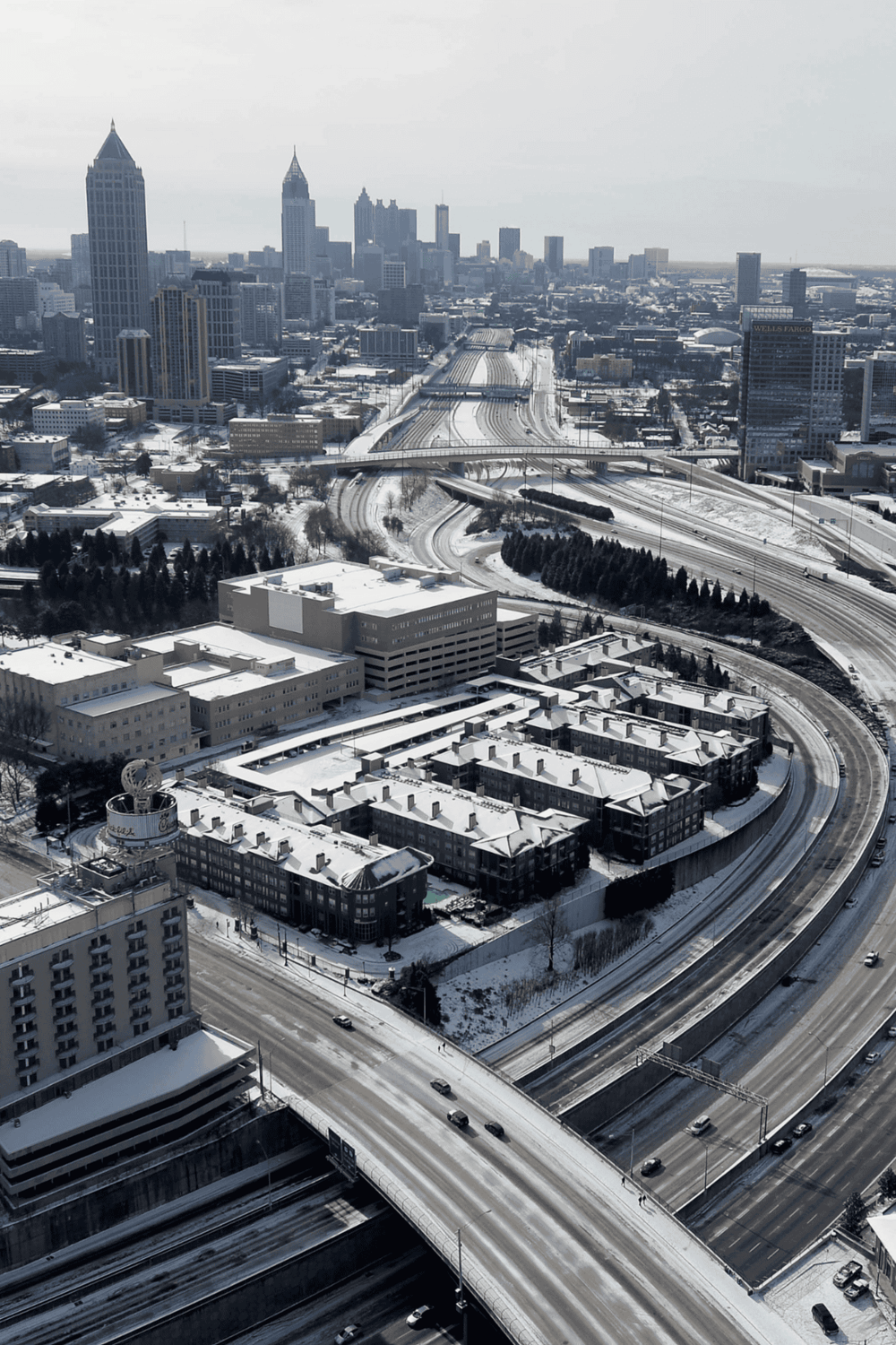 Snow-covered downtown Atlanta skyline with major highways, buildings, and skyscrapers in winter.