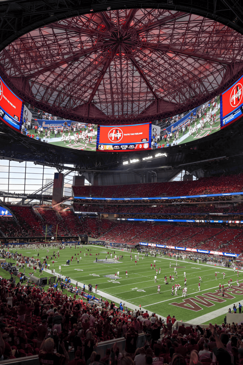 - Lofted football stadium with digital screens and red seating, high-energy sports environment.