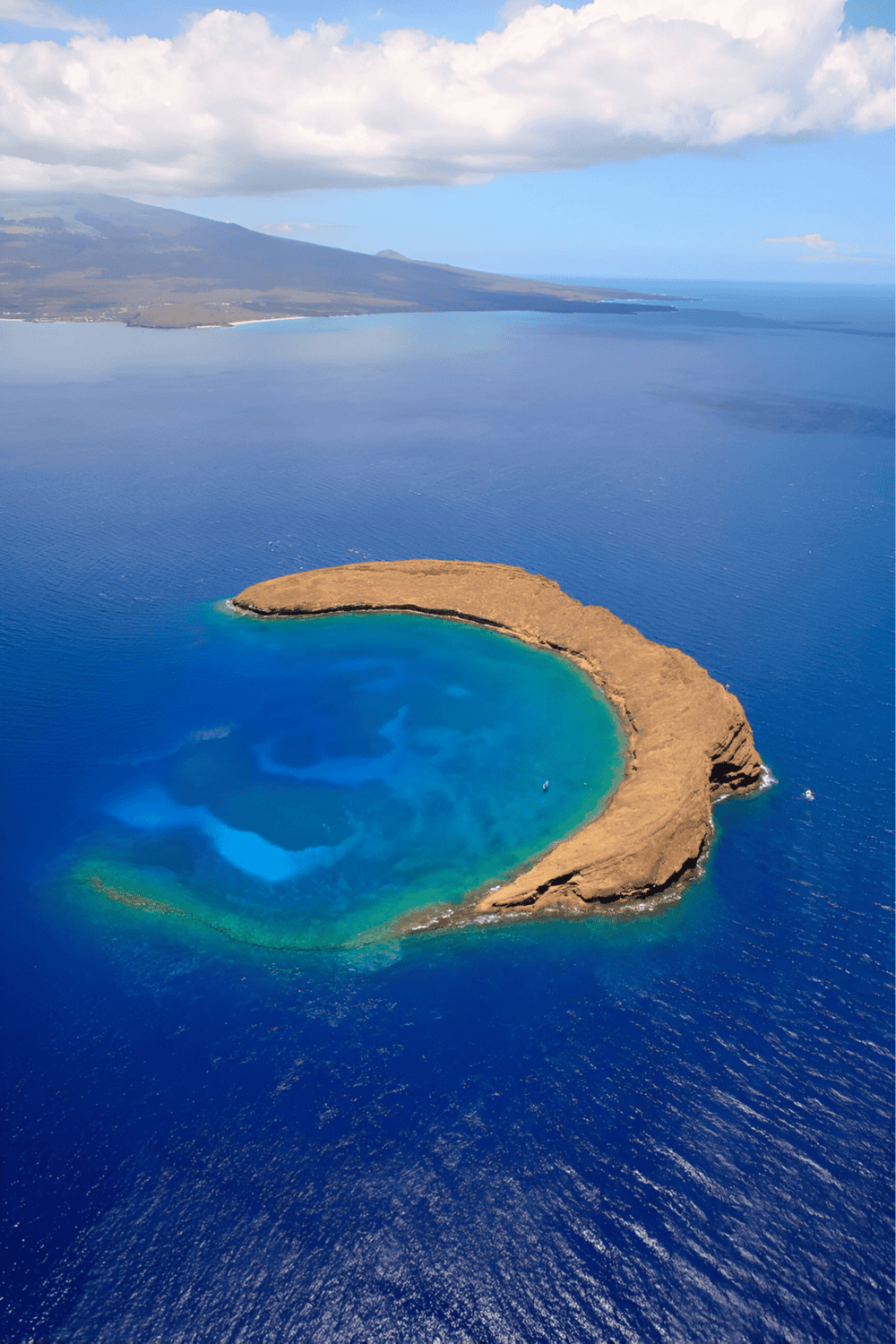 Secluded coastal island with vibrant blue and turquoise waters, scenic landscape, and clear skies.