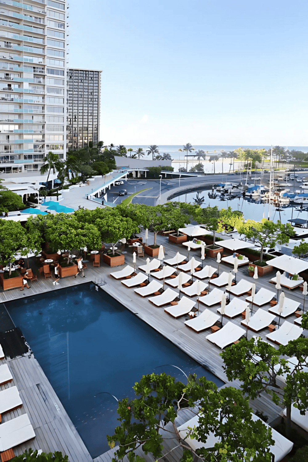 Poolside lounge chairs and marina view at luxury waterfront hotel.