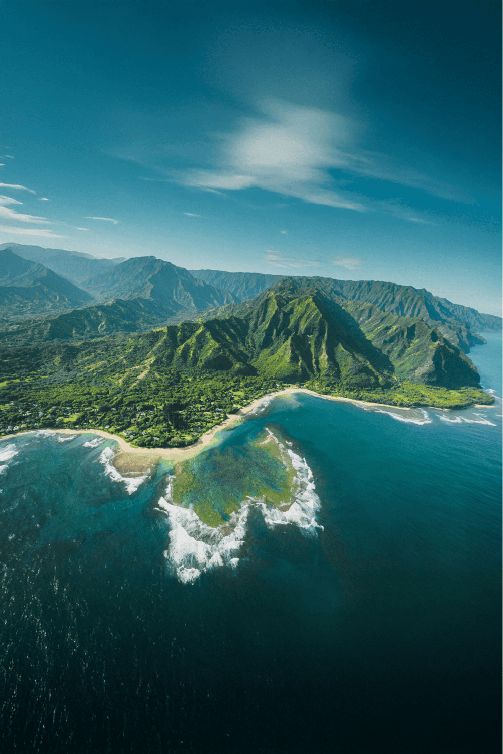 Lush green coastal mountains with vibrant ocean waters and scenic shoreline, Hawaii travel destination.