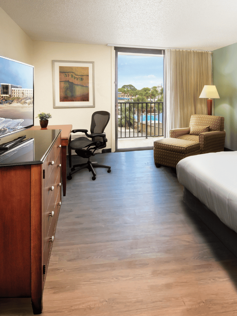 Comfortable hotel room with work desk, balcony, and ocean view, perfect for travelers seeking relaxation and convenience.