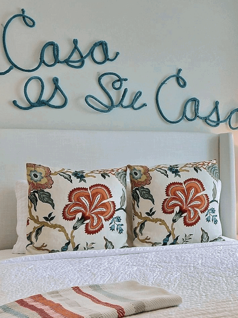 Colorful embroidered pillows on a bed with a floral design, and a cozy throw blanket.