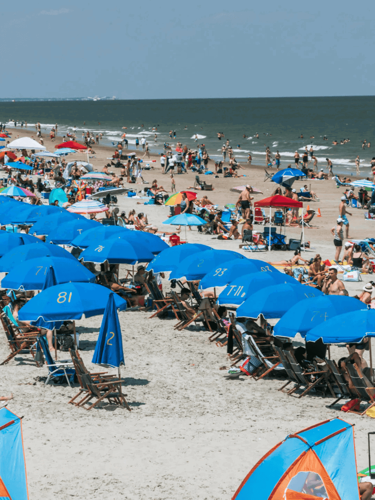 Colorful beach scene with umbrellas, sunbathers, and ocean waves at a popular seaside destination.