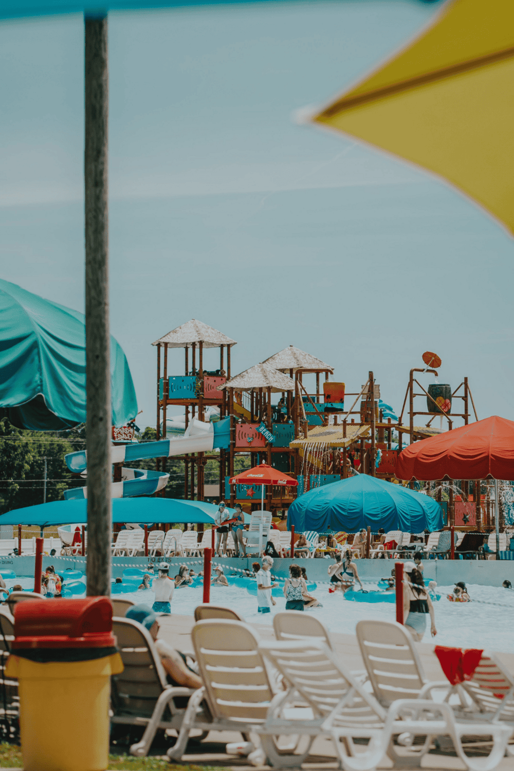 Colorful water park with slides, umbrellas, and families enjoying a summer day.