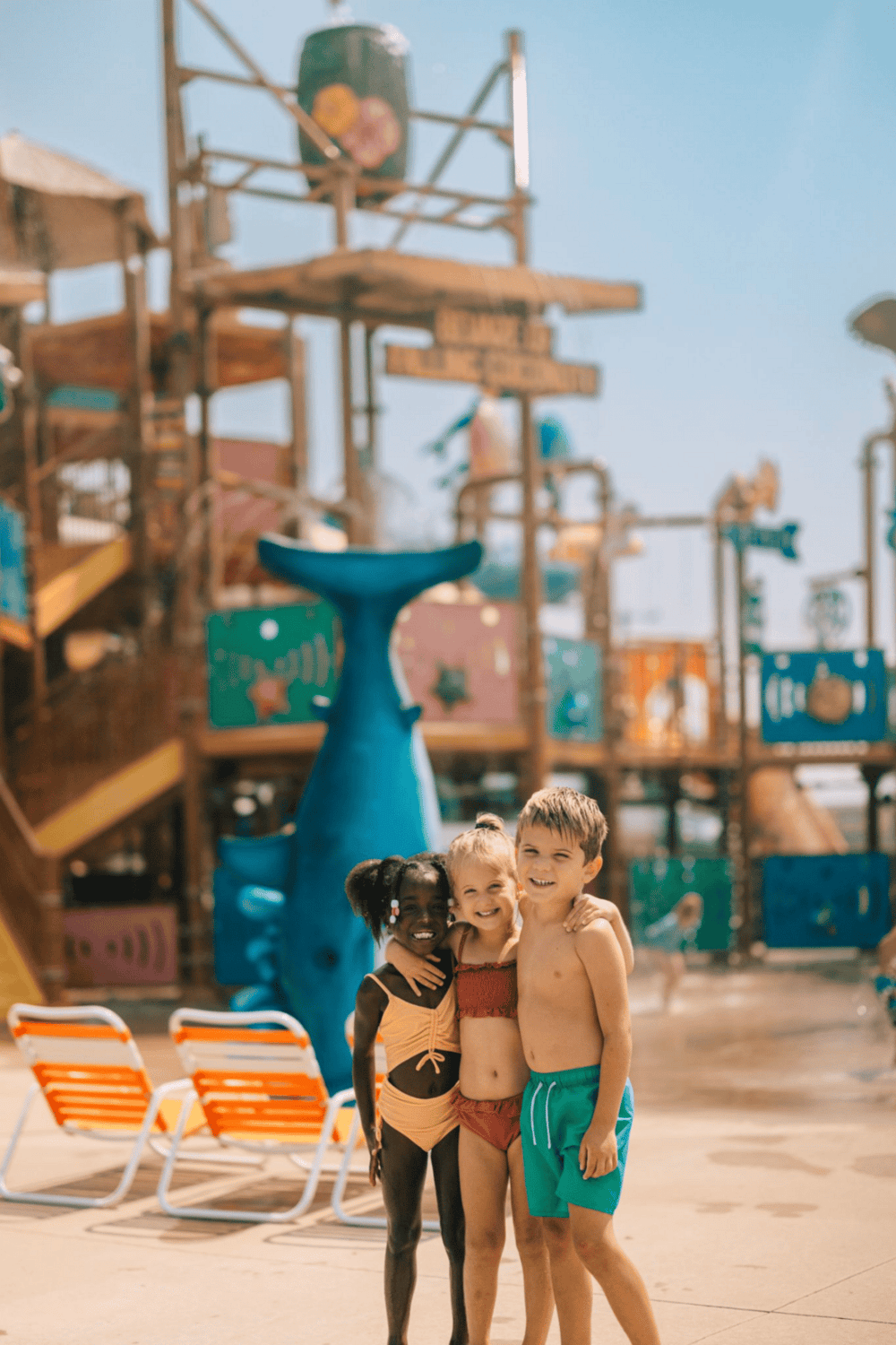 Children enjoying a day at a colorful water park with play structures and bright sunshine.