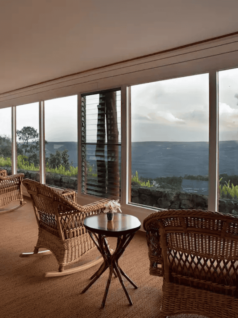 Serene mountain view from cozy indoor seating with wicker chairs and glass windows.