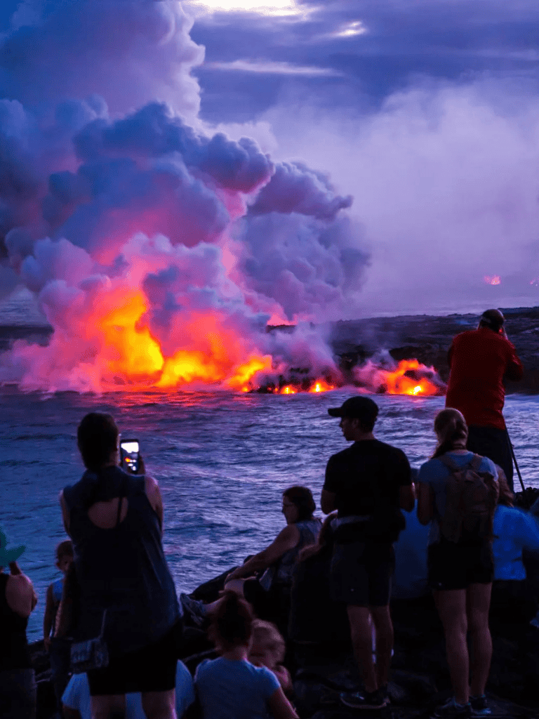 Volcanic eruption at night with onlookers capturing the scene, showcasing adventure and nature's power.
