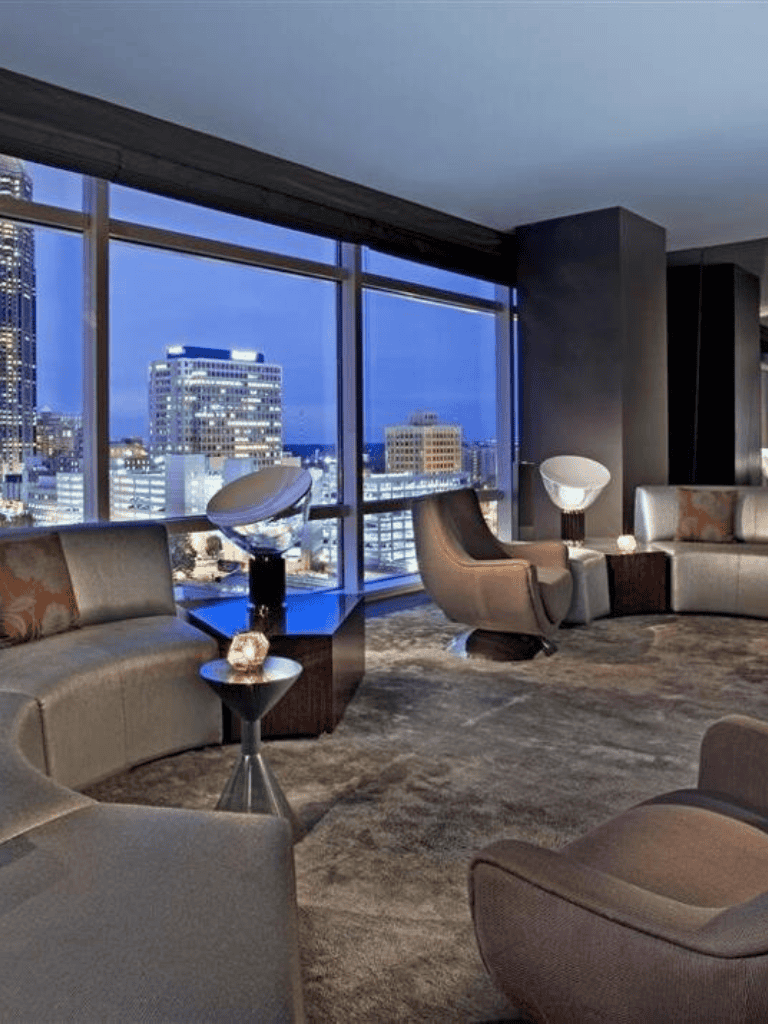 Elegant modern office lounge with city skyline view at dusk, featuring stylish seating and ambient lighting.