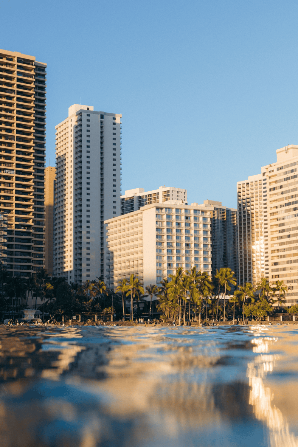 Modern city skyline with high-rise buildings on waterfront at sunset.