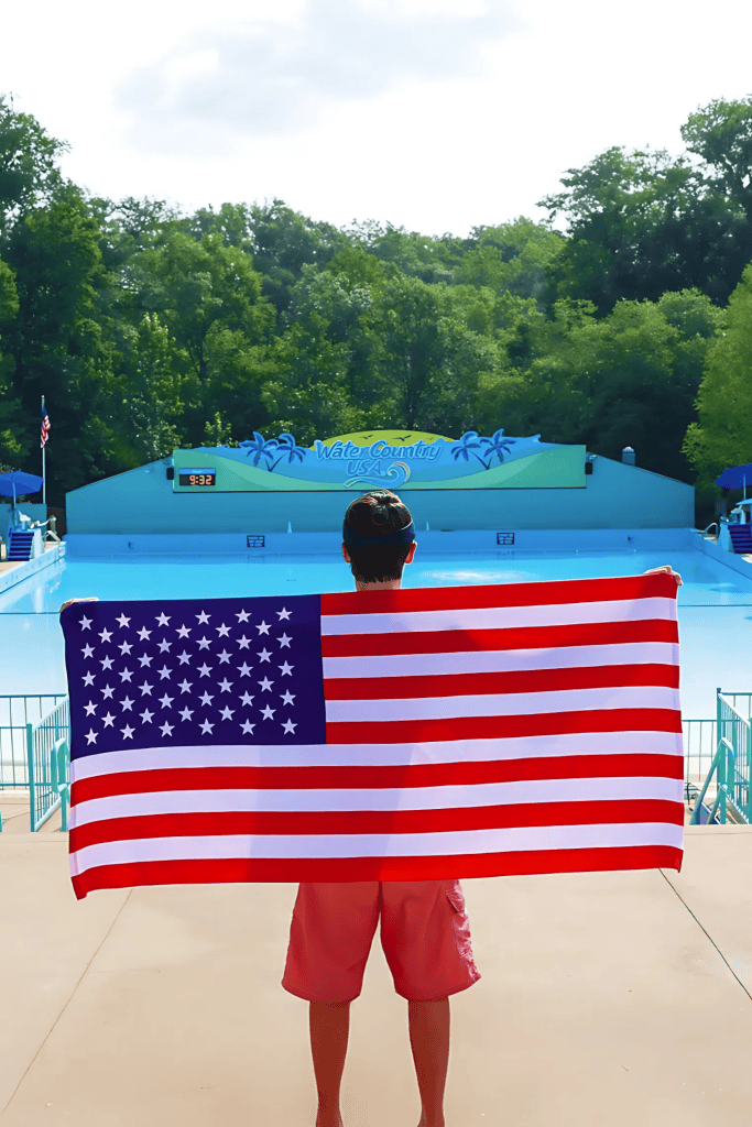 Person holding American flag beside empty pool on a bright summer day.