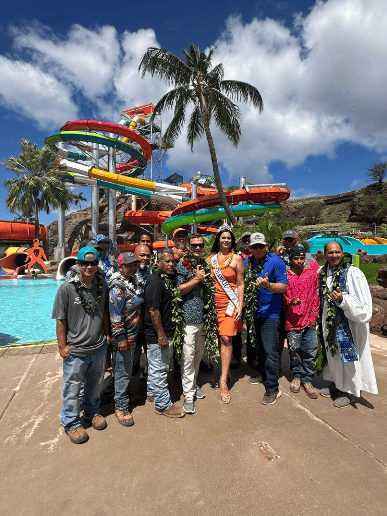 Colorful water park with slides and tropical scenery, featuring a group celebrating outdoors.