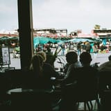 Busy market scene with outdoor vendors and shoppers, view from a café window in Morocco.