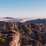 Breathtaking mountain landscape overlooking the ocean with clear skies and rugged cliffs.