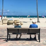 Senior couple sitting on a bench enjoying a sunny day at Hollywood Beach, Florida.