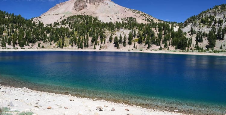 Serene mountain lake surrounded by pine trees and rugged landscape, perfect for outdoor adventure and nature exploration.