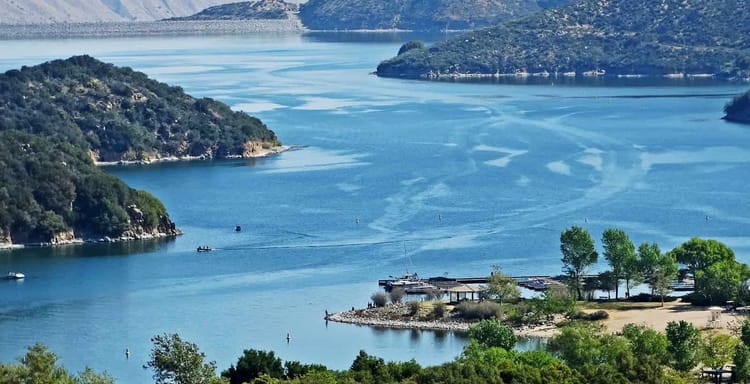 Scenic lake view with mountains, boats, and lush greenery, perfect for outdoor adventures and nature exploration.