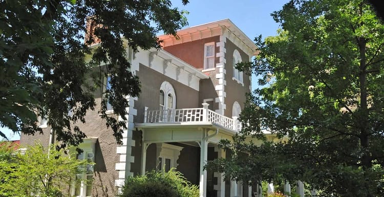 Victorian-style historic house surrounded by lush greenery and mature trees in Centerton, Arkansas.