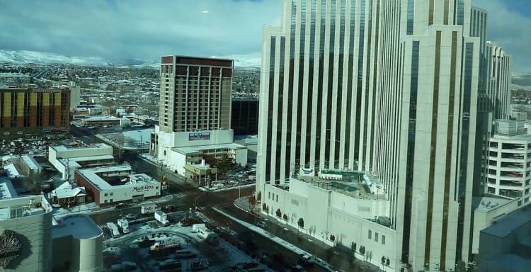 Downtown Reno winter skyline with modern skyscrapers and snowy Sierra Nevada mountains.