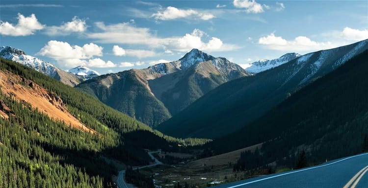 Breathtaking mountain landscape with lush green forests and snow-capped peaks in the background.
