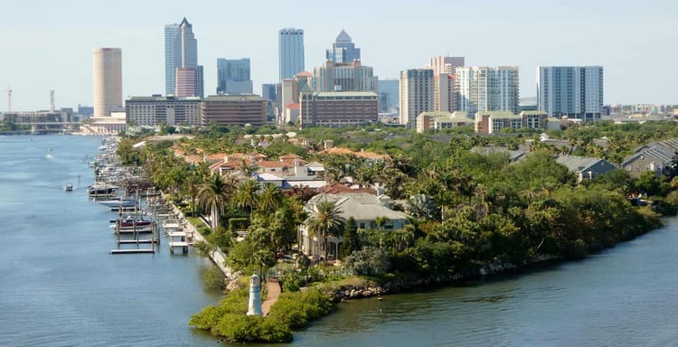 Bayside city skyline with waterfront homes and boats in Tampa, Florida, featuring modern high-rise buildings.