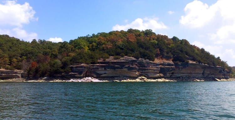 Serene river with layered rock cliffs and lush autumn foliage at QuestForDirections scenic spot.