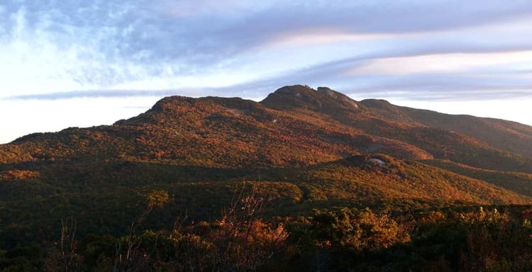 Stunning mountain landscape with colorful autumn foliage and a partly cloudy sky.