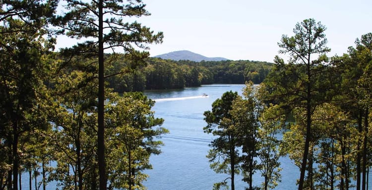 Serene lake scene with lush trees and mountains, ideal for outdoor adventures and nature exploration.