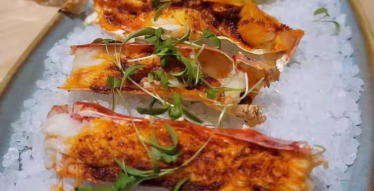 Fresh grilled seafood platter with lemon, served on ice with a side of pasta and a beverage. Perfect for seafood lovers and outdoor dining.