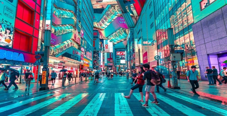 Vibrant Tokyo street scene with neon signs, busy crosswalk, and pedestrians in summer rain.