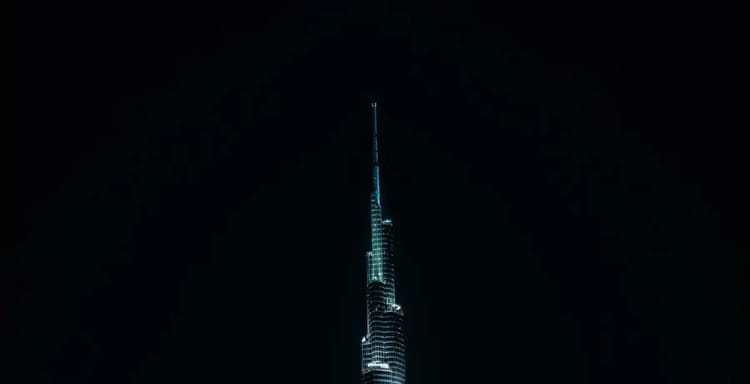 Brightly lit Dubai skyscraper at night, showcasing futuristic architecture and city skyline.