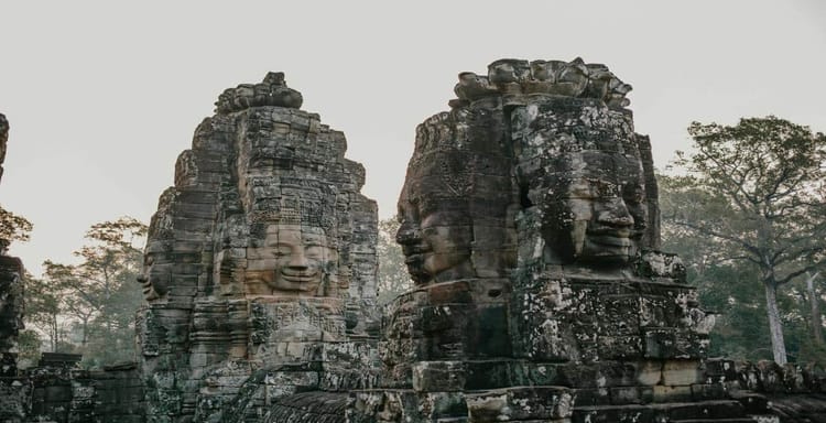 Ancient Angkor Wat stone faces at sunrise in Cambodia, showcasing historical and cultural tourism.