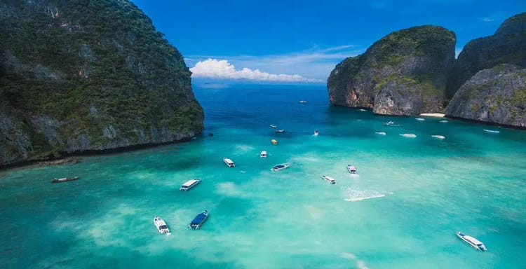 Turquoise bay with boats near limestone cliffs, scenic travel destination, Thailand island paradise.