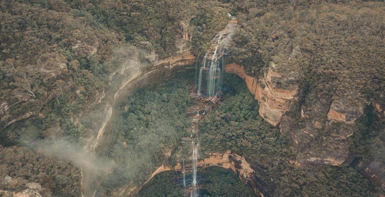 Stunning aerial view of a waterfall in a lush, green forest landscape at QuestForDirections.
