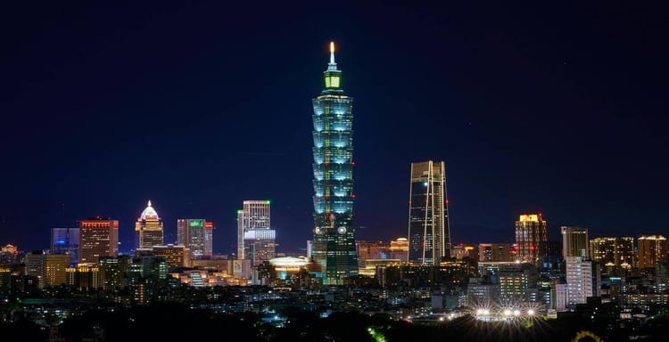 Bright Taipei 101 skyscraper illuminated at night in Taiwan, city skyline with vibrant lights.