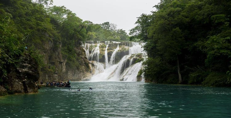Vibrant waterfall surrounded by lush green trees at QuestForDirections adventure travel site.