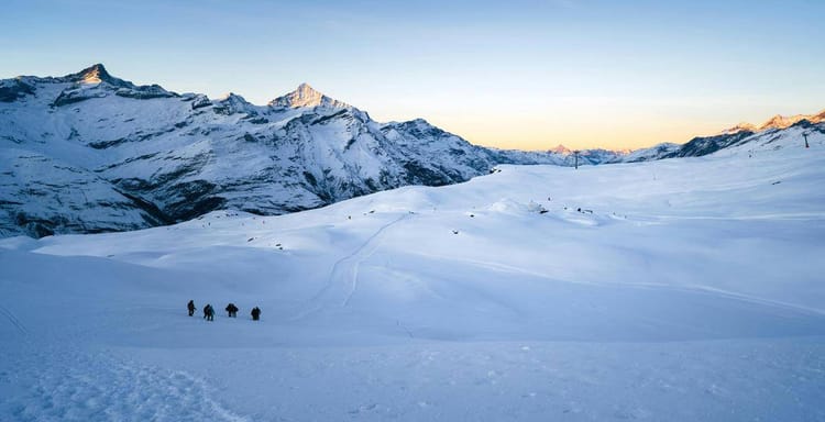 Snowy mountain landscape with hikers in winter, ideal for outdoor adventure and travel destinations.