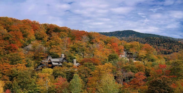 Colorful fall foliage with scenic mountains and rustic homes in autumn.