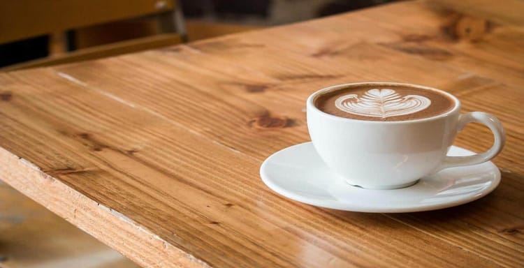 1. Coffee cup with latte art on wooden table, cozy coffee shop ambiance.