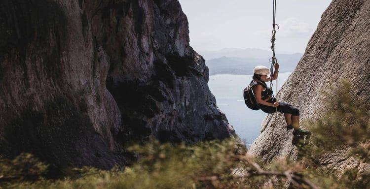 1. Female rock climber swinging on a mountain rescue swing with scenic landscape background.