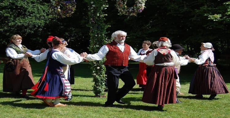 Traditional folk dance with people in historic costumes outdoors, showcasing cultural heritage.
