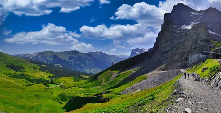 Vibrant mountain landscape with hiking trail, lush green valleys, and dramatic peaks. Perfect for adventure and outdoor travel guides.