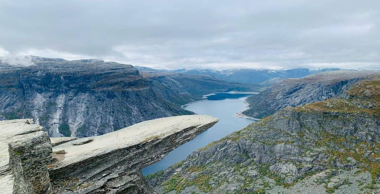 Breathtaking mountain landscape over a fjord with dramatic cliffs and cloudy sky.
