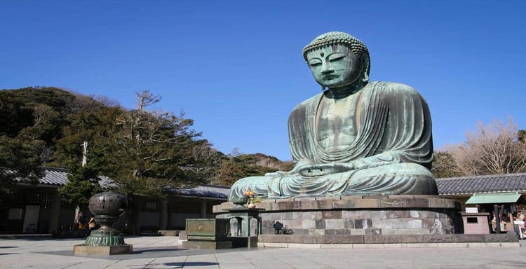 Huge bronze Buddha statue at historical temple grounds in Japan, peaceful spiritual site for visitors.