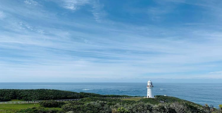 Lighthouse overlooking the ocean on scenic coastal landscape for travel navigation.